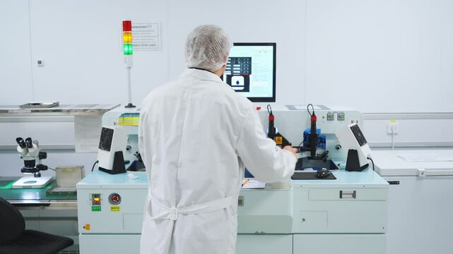 An engineer worker technician at a modern chip factory controls process of placing chips on a board using a computer. Production line of high-tech diodes, transistors, microcircuits. High-tech machine