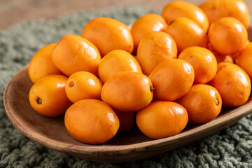 Fresh Brazilian Seriguela Fruits on a Wooden Tray with Traditional Fabric