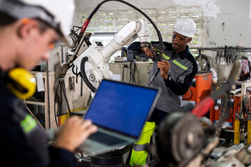 Robotics control engineers setting and maintain spare parts of industrial robot arm controller in production plant factory