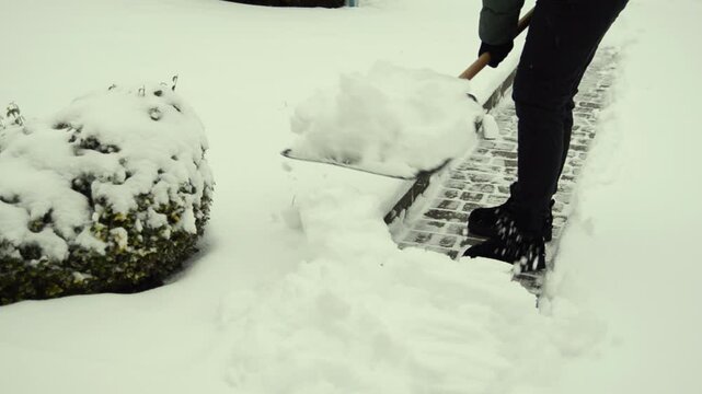 Woman cleaning her snowed back yard with plastic shovel. Winter concept.