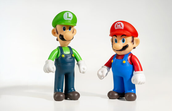 Luigi and Super Mario Bros figurines standing on white background