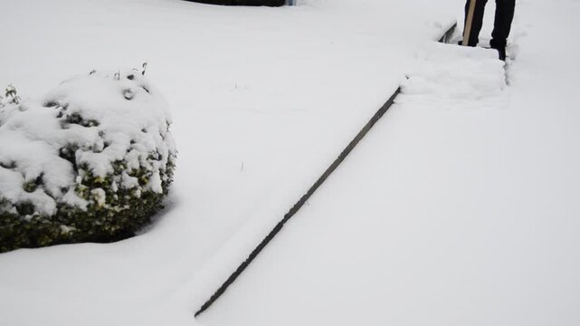 Woman cleaning her snowed back yard with plastic shovel. Winter concept.