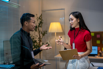 Fototapeta premium Asian business people having conversation about work in office at night