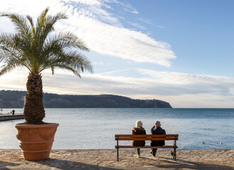 Older couple sitting by the sea and looking at the horizon