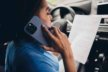 Young woman multitasking with phone and document in car, embracing urban life