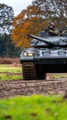 Fototapeta premium Challenger main battle tank advances along a winding road amid lush fields and vibrant autumn trees under clear skies