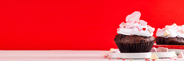 Valentine day tasty double chocolate cupcakes treat with whipped cream, heart shaped marshmallow and sugar sprinkles