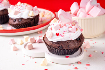 Valentine day tasty double chocolate cupcakes treat with whipped cream, heart shaped marshmallow and sugar sprinkles