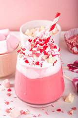 Valentine day pink hot chocolate or milkshake, tasty sweet red velvet, or berry sweet chocolate drink, milk protein shake with a lot of whipped cream, heart shaped marshmallow and sugar sprinkles