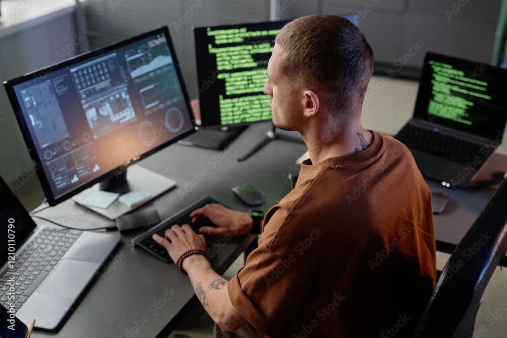 Poster side view of senior male it developer typing on keyboard of desktop computer working at desk in mode