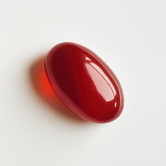 Bright red glossy jelly bean resting on a white surface, showcasing vibrant color and smooth texture