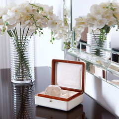 Jewelry box with decorative glass ball inside stands on console table. Lamp and vase with orchids...
