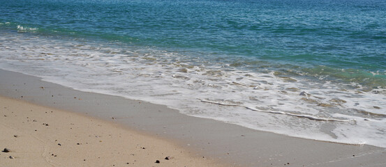 Soft blue ocean wave, sandy beach, serene coast, tranquil seaside, tropical shoreline, clean sand, peaceful waves, gentle surf, calm ocean, beach scenery.