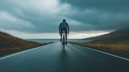 Obraz premium Cyclist sprints on a wet road along the coast under a dramatic sky