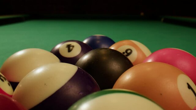 Young man playing American billiard pool poule close-up. Colorful balls on green billiards table .Billiard balls with numbers on a pool table. Billiards team sport.