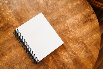 spiral bound book laying closed on a wooden table. blank paper for project concept presentation...