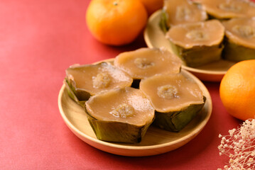 Sticky rice cake (Nian Gao), Chinese New Year cake and orange fruit on red background