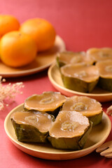 Sticky rice cake (Nian Gao), Chinese New Year cake and orange fruit on red background