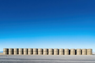 Row of hay bales stacked under a bright blue sky.