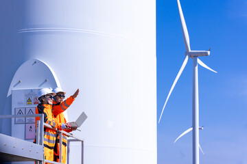 Team of male and female engineers discuss for maintenance of wind turbines at windmill field farm. Group of engineers workers working at wind turbines farm. Alternative energy, environmental friendly.
