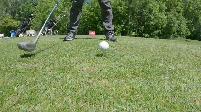 Slow motion of person getting ready then hit golf balls with grey colored club
