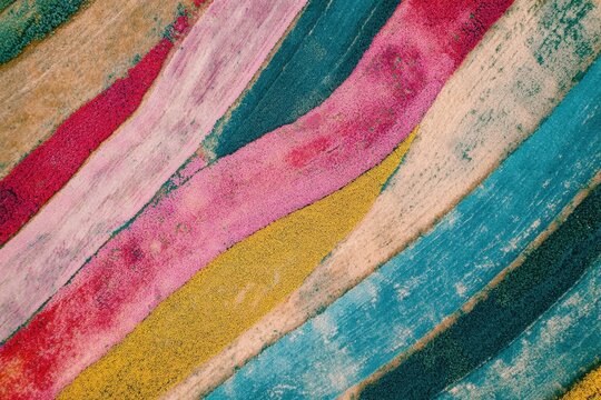 A scenic farm field with alternating crops creating colorful patterns.