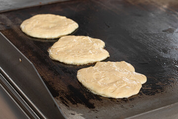 Pancakes batter baking on the frying pan in kitchen