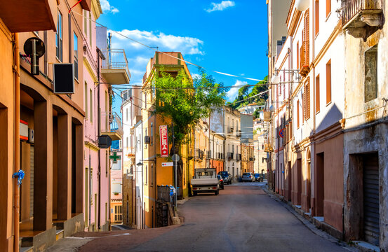 Idyllic, deserted street scene in the picturesque mountain village of Baunei on the Italian Mediterranean island of Sardinia. Main street lined with colorfully painted old houses on a hot summer day.