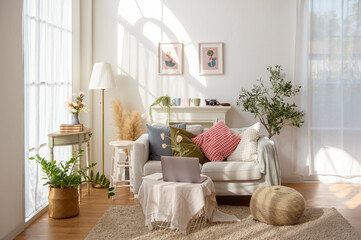 Cozy Living Room Setup With Plants, Artwork, and a Laptop Near Bright Windows in a Warm Atmosphere