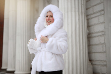 Obraz premium happy young female in white fur coat and hat 