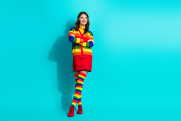 Young woman in colorful rainbow outfit on teal background expressing individuality and style