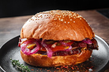 A delicious sesame seed burger bun filled with juicy grilled meat, topped with vibrant red onions, bell peppers, and fresh herbs. Perfect for food photography and culinary projects.