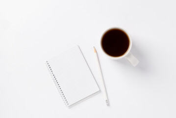 Notebook, pencil and white cup with black coffee on white background. Cleanliness concept. White monochrome background with notebook, pencil and cup of coffee