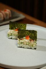 Sushi roll with salmon, seaweed and caviar on white plate