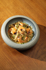 Seafood pasta with shrimps in bowl on wooden table