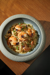 Seafood pasta with shrimps in bowl on wooden table