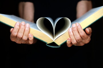 Close-up front view of a Woman holding an open book with pages folded into a heart shape