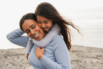 Happy latin mother having tender moment with little daughter on the beach - Family love concept - Mom and child - Focus on faces