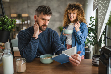 focused boyfriend read book while have breakfast with girlfriend