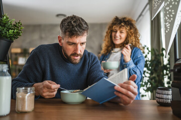 focused boyfriend read book while have breakfast with girlfriend