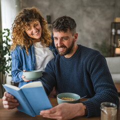 boyfriend and girlfriend read book together on breakfast at home