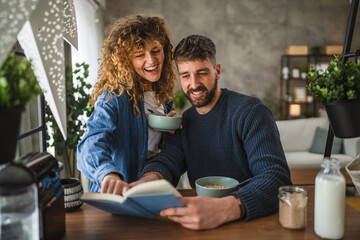 boyfriend and girlfriend read book together on breakfast at home