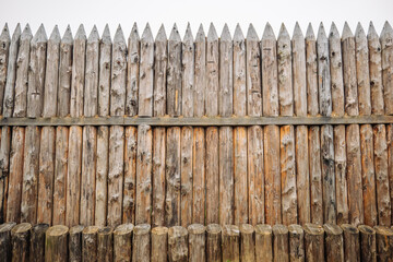Close up of a sturdy, sharpened wooden palisade forming a robust barrier, showcasing traditional fortification techniques in a historical setting