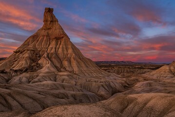 Stunning view of a unique rock formation in Bardenas Reales, Spain, under a vibrant sunset sky
