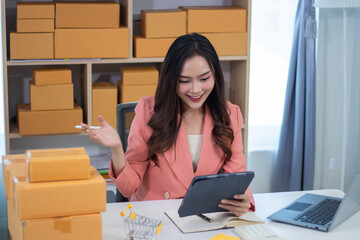 Beautiful girl working in online sales Business owners using tablets or laptops check online orders...