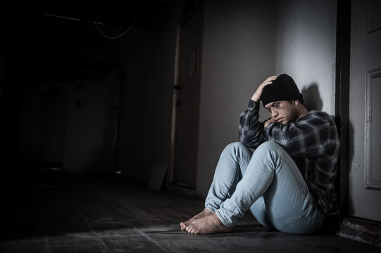 A middle-aged man sits in front of the door of a room, depressed and anxious after he took drugs. - Powered by Adobe
