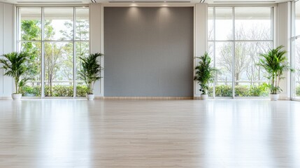 Empty bright room with large windows, plants, and grey wall; ideal for event advertising