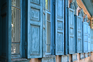 Wooden shutters of an old single-story traditional house. The wood is painted blue. City of Almaty, streets.