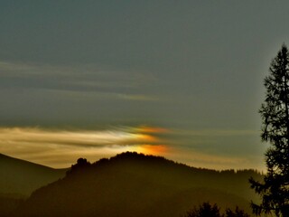 Colorful picturesque sky with Parhelion on Cirrostratus clouds over misty Tatras, Tatra Mountains in Poland and dark branches trees in autumn. Topics: optical phenomenon, air space, weather