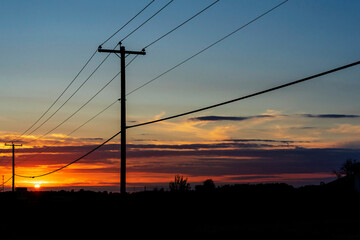 Power transmission line poles against the sky at sunset
